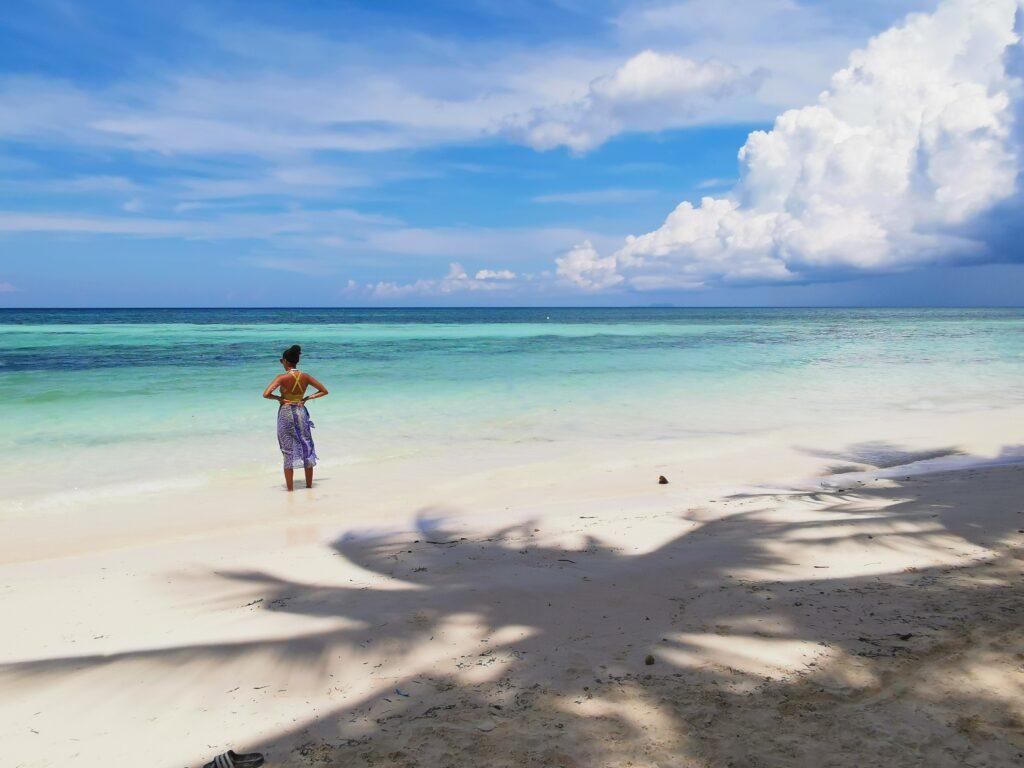 a women standing on a white sand beach